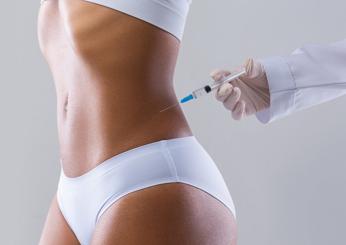 Cropped of young well fit black woman having injection in her waist, beauty procedure in saloon, panorama with copy space